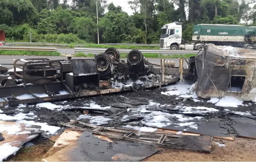  Caminhão carregado com MDF tomba nas margens de rodovia e pega fogo